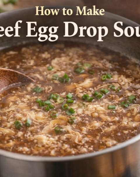 Bowl of beef egg drop soup with soft egg ribbons and green onions served hot