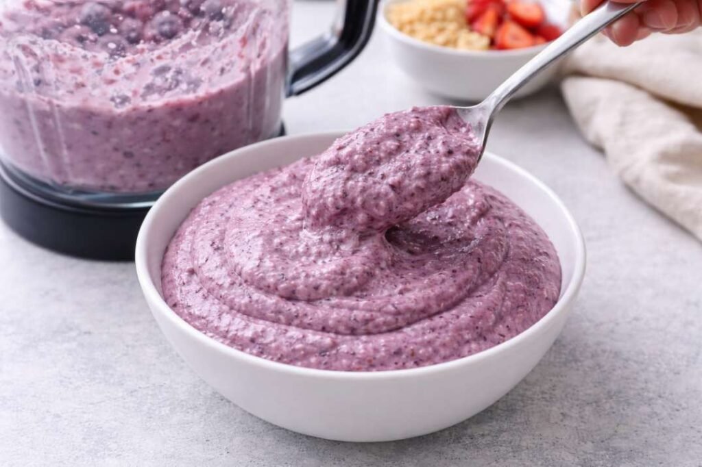 Best Vanilla Berry Smoothie Bowl Recipe for a Thick, Spoon able Texture 7 Scooping thick berry smoothie into bowl