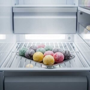 Wrapped ice cream balls freezing in a tray before frying