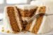 Moist carrot cake slice with cream cheese frosting and fork cutting into soft layers