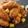 Crispy chicken wings coated in homemade Wingstop Hawaiian sauce recipe served on a slate board with pineapple garnish