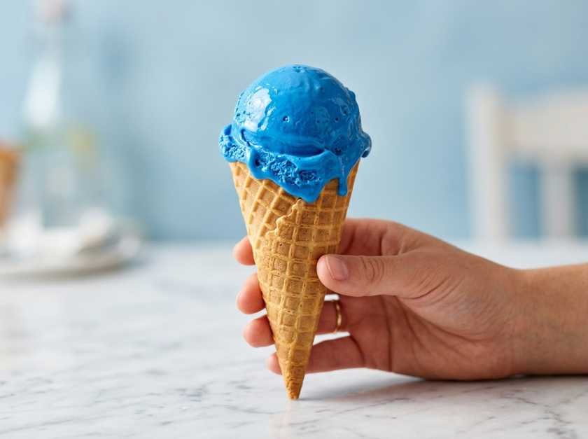 The Best Blue Raspberry Ice Cream Recipe (No Machine Needed) 2 A scoop of homemade no-churn blue raspberry ice cream in a waffle cone, showing vivid electric blue color and creamy texture