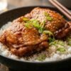 Lee Kum Kee char siu chicken thighs with sticky caramelized glaze in a dark ceramic bowl over jasmine rice with scallions and sesame seeds