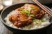 Lee Kum Kee char siu chicken thighs with sticky caramelized glaze in a dark ceramic bowl over jasmine rice with scallions and sesame seeds