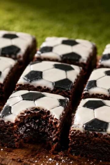Little Debbie soccer-themed brownies recipe with fudgy chocolate interior, white vanilla icing, and black soccer ball decoration on a rustic wooden board