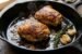 Pan seared chicken thighs in a cast-iron skillet with crispy golden brown skin, fresh thyme, and smashed garlic cloves
