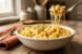 Creamy Texas Roadhouse mac and cheese recipe in a rustic white bowl with golden cheddar cheese sauce and a fork pulling melted cheese strings